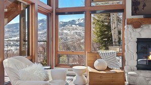 A cozy room with large windows offering a mountain view, a fireplace, and comfortable seating. - Snowmass Village Retreat, Pet-Friendly, Hot Tub, Game Room & Rooftop Deck Near Base Village (Snowmass Village)