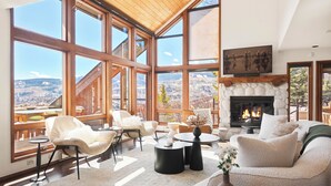 A spacious living area with large windows, a fireplace, and a view of the mountains. - Snowmass Village Retreat, Pet-Friendly, Hot Tub, Game Room & Rooftop Deck Near Base Village (Snowmass Village)