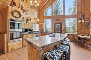A wooden cabin interior with a kitchen, dining area, and large windows. - Wonderful 4-bedroom cabin in charming Duck Creek Village (Duck Creek Village)