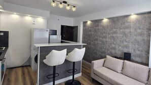 Ein zeitgemäßer Wohnraum mit einer Küche, einem Sofa und zwei Barhocker.