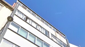 Ein mehrstöckiges Gebäude mit Klimaanlagen, großen Fenstern und blauem Himmel.