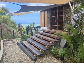 A wooden staircase leading to a house with a view of the ocean.