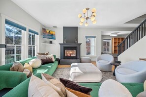 Ein modernes Wohnzimmer mit Kamin, grünen Sofas und einer Treppe.
