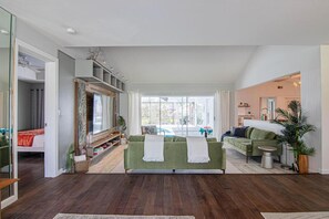 Un salón amplio con un sofá grande, una televisión y vistas a una piscina.