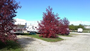A gravel parking area with RVs and a white building in the background.