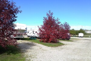 A gravel parking area with RVs and a white building in the background.