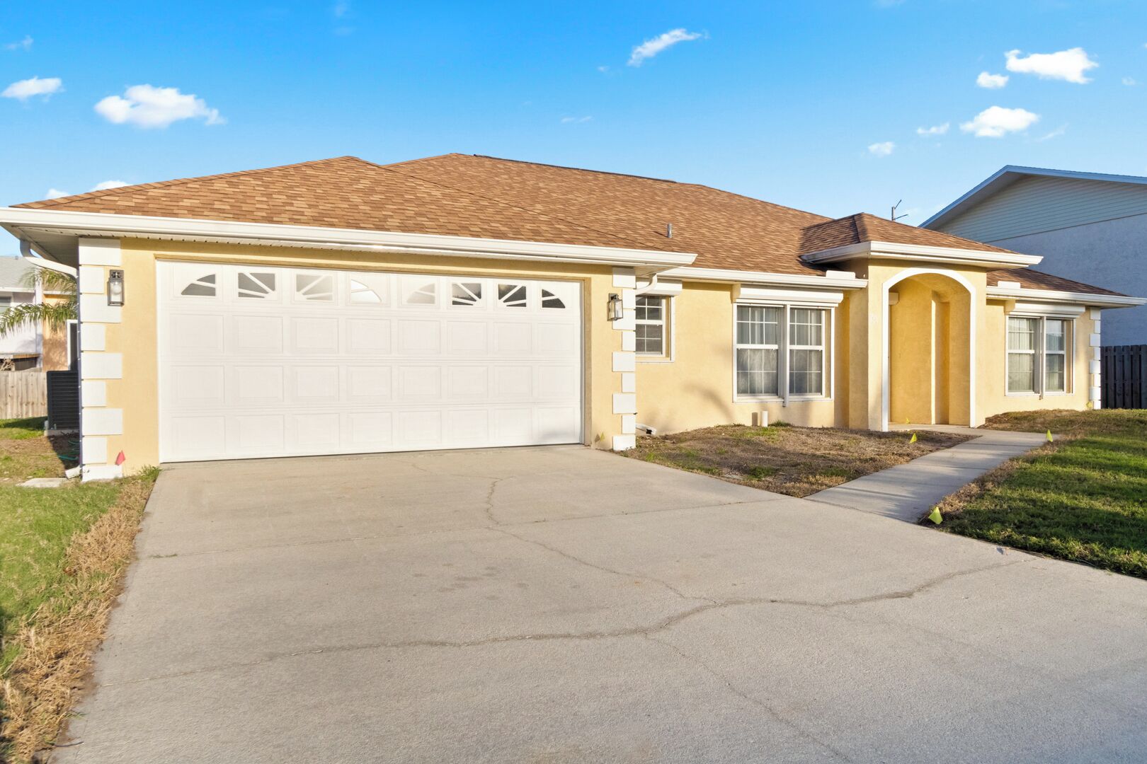 A residential house with a garage, a driveway, and a lawn.