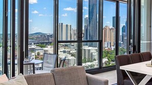 Une chambre d’hôtel moderne avec de grandes fenêtres, un coin repas et une vue sur le paysage urbain.