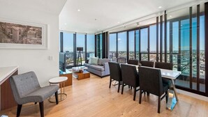 Un salon moderne avec un coin repas, de grandes fenêtres et une vue sur la ville.