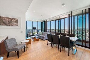 A modern living room with a dining area, large windows, and a city view. - Skyline Apartment in Fortitude Valley (Brisbane)