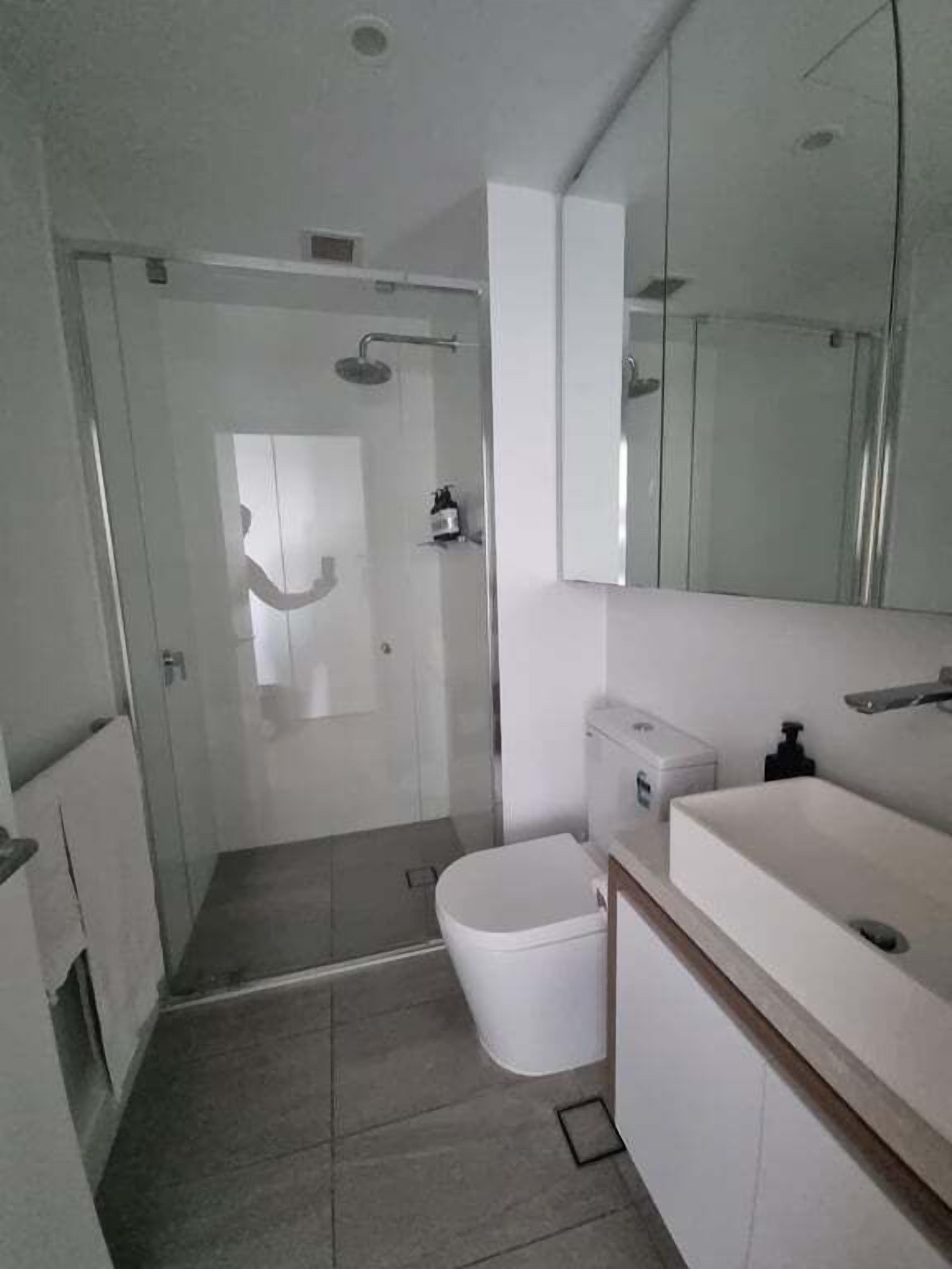 A modern bathroom with a shower, toilet, and sink.