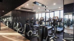 Une salle de sport équipée de tapis de course, d’appareils elliptiques et de vélos d’exercice.