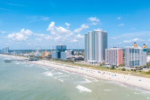 A coastal cityscape with a beach, high-rise buildings, and a Ferris wheel. - Oceanfront condo with pool, hot tub, lazy river - direct beach access (Myrtle Beach)