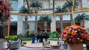 A spacious atrium with a stage, palm trees, and a large floral arrangement. - Deluxe Apartment Balcony Sea View (Parañaque)