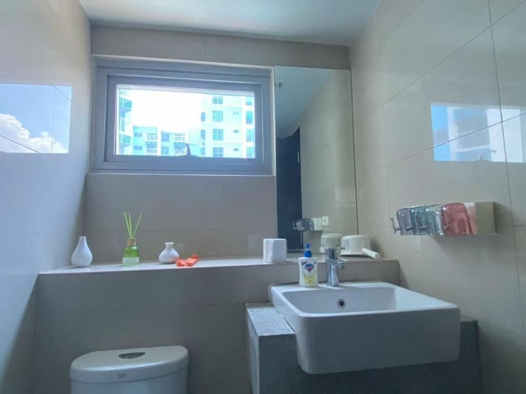 A bathroom with a window, a sink, a toilet, and a mirror.