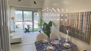 A dining area with a table set for four, a sofa, and a balcony with outdoor seating. - Deluxe Apartment Balcony Sea View (Parañaque)