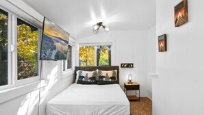 Een slaapkamer met een bed, nachtkastje, lamp en kunst aan de wanden.