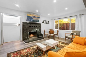Una sala de estar con chimenea, un sofá, una mesa de centro y un comedor.