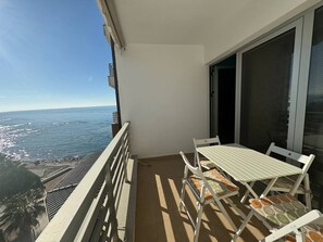 Un balcon avec une table et des chaises, offrant une vue sur la côte.