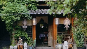 A traditional wooden building with a tiled roof, a wooden door, and a small porch area with potted plants and decorative items. - Yayunju Inn (Shanghai)