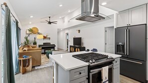 A modern kitchen with a central island, a built-in stove, and a large refrigerator. - Eastside Keys by Avantstay Bright East Austin Stay + Backyard Dining + Near 6th St and Downtown (Austin)