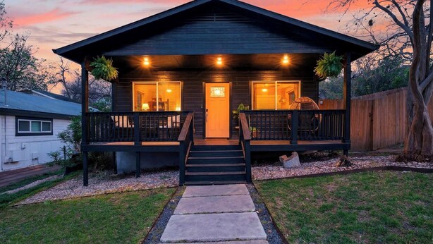 A two-story wooden house with a porch, a front door, and a staircase leading to the entrance. - Eastside Keys by Avantstay Bright East Austin Stay + Backyard Dining + Near 6th St and Downtown (Austin)