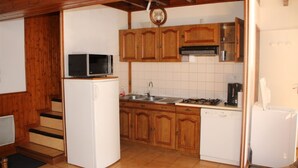 Een kleine keuken met houten kastjes, een magnetron, een spoelbak en een vaatwasser.