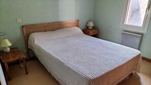 Een slaapkamer met een bed, nachtkastje, lamp en een raam.