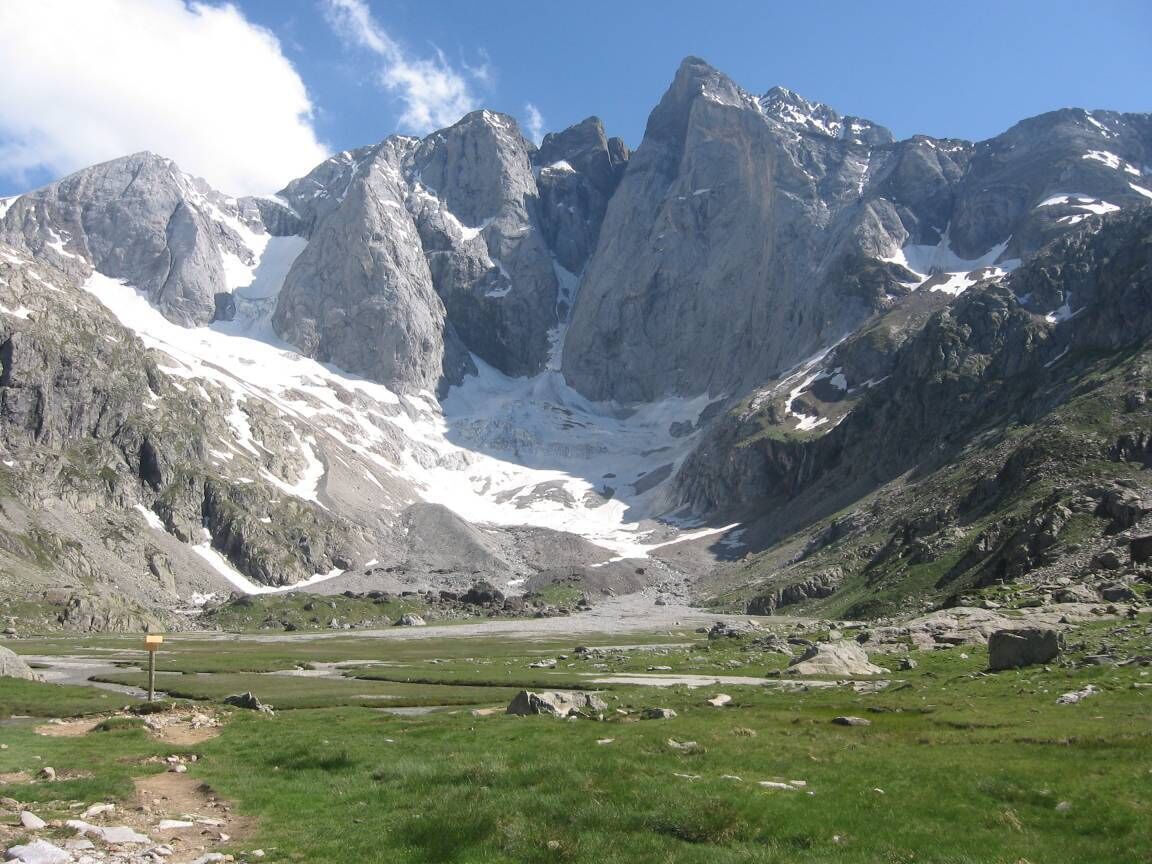 A mountainous landscape with a valley, rocky terrain, and a clear sky.