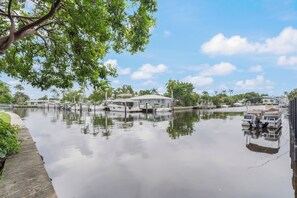 A calm water body with boats docked, a house with a white roof, and a tree with green leaves. - Beach Getaway in Pompano! 2BR/2BA Condo – Walk to Beach & Restaurants, groceries (Pompano Beach)