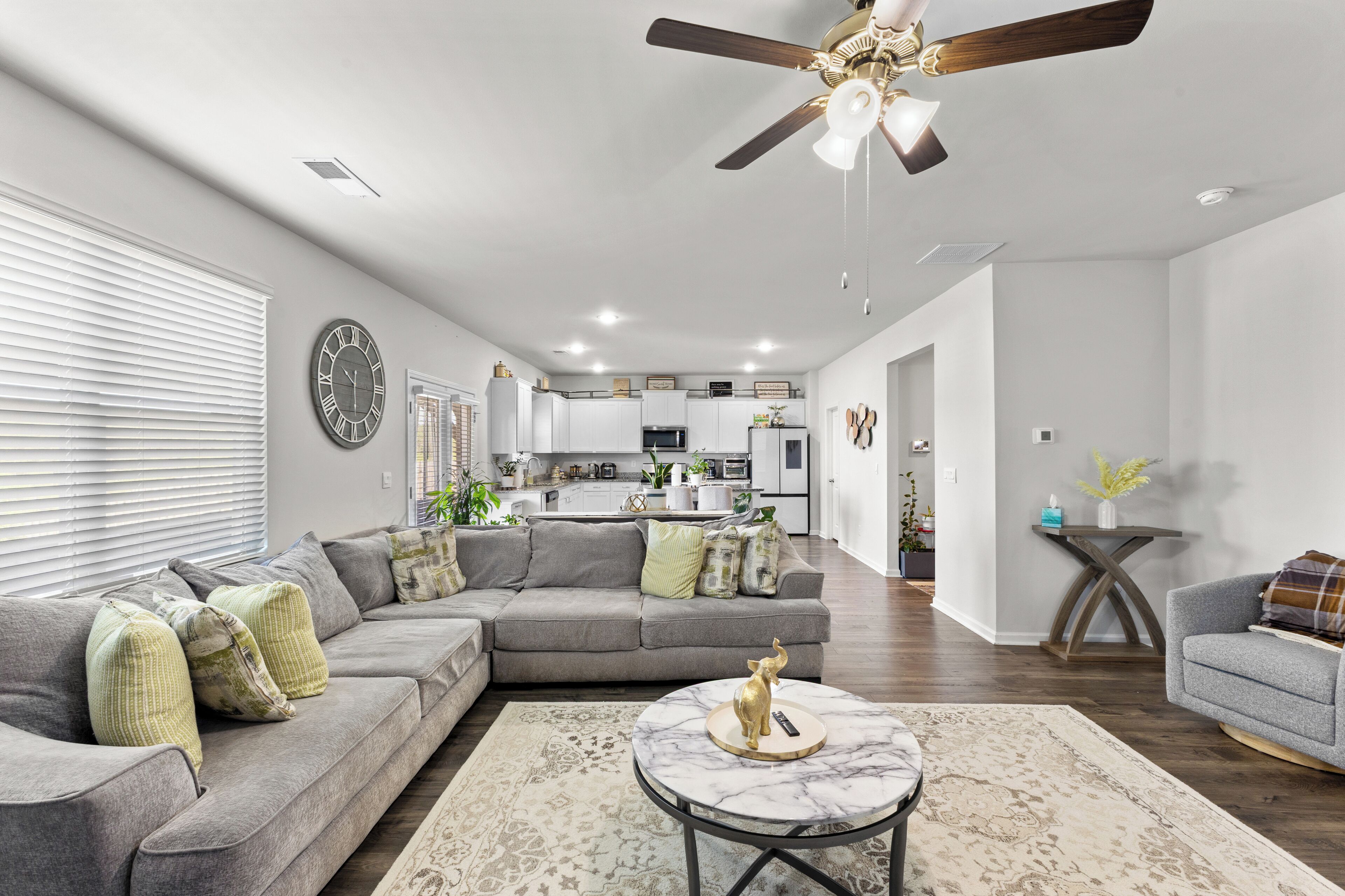 A modern living room with a sectional sofa, a round coffee table, and a ceiling fan.
