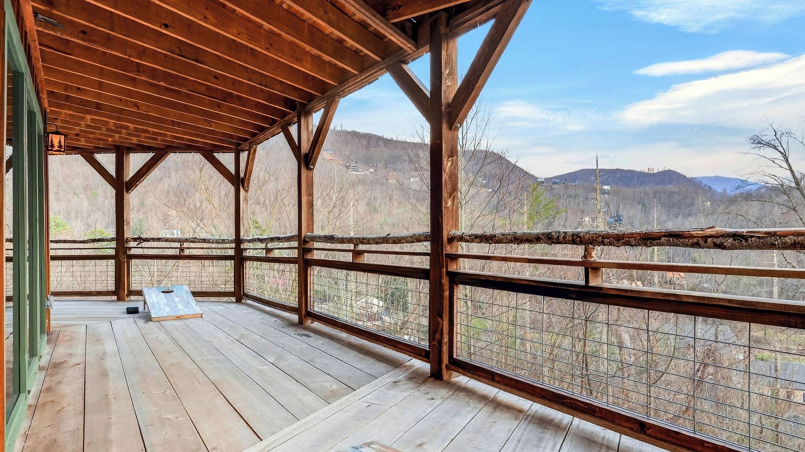 Eine Holzdar Terrasse mit Metallgeländer, mit Blick auf eine Berglandschaft.