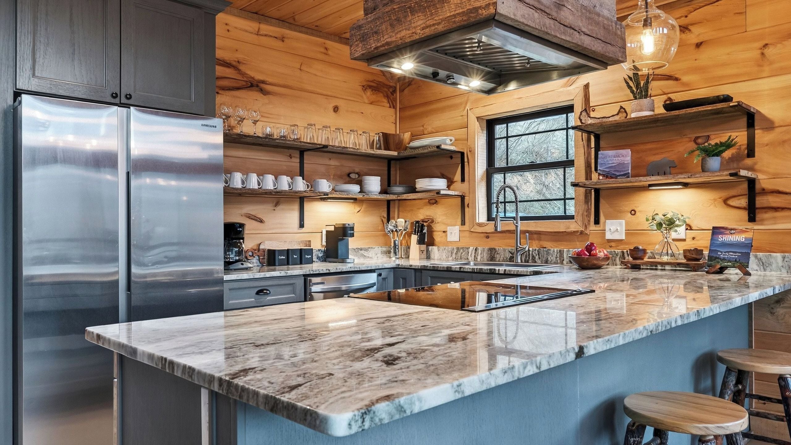 A modern kitchen with a marble countertop, stainless steel appliances, wooden shelves, and a large window.