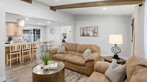 Un salon avec un canapé, une table basse et une lampe. Il y a également un coin repas avec une table et des chaises.