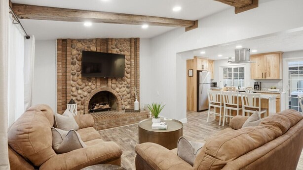 Un salon doté d’une cheminée, d’un canapé, d’une table basse et d’un coin cuisine avec des meubles en bois et un réfrigérateur.