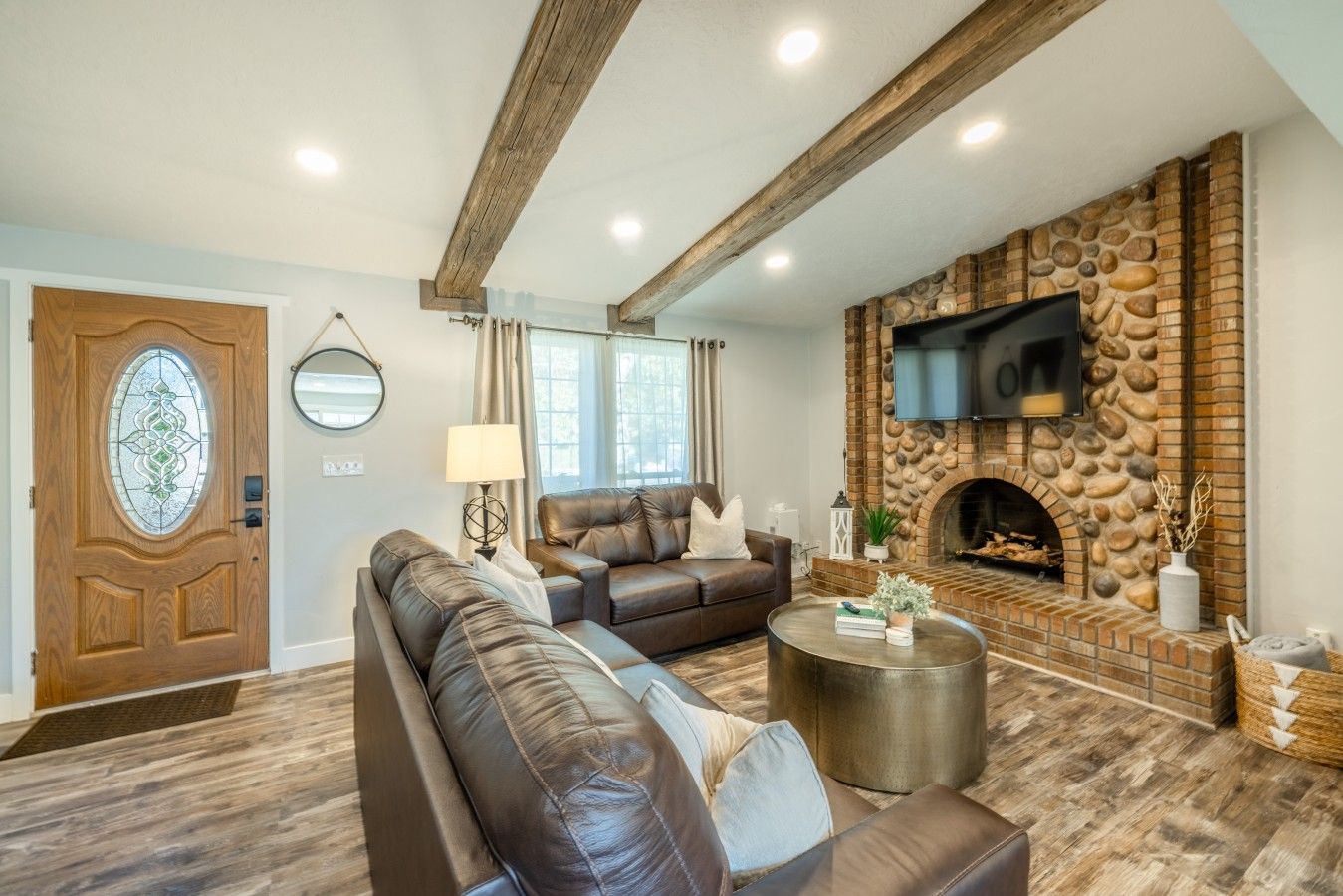 A living room with a stone fireplace, leather sofas, and a round coffee table.