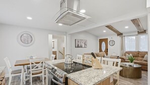 Une cuisine moderne dotée d’un îlot central, de meubles blancs et d’un coin repas avec des chaises blanches.