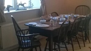 A dining room with a rectangular table set for six, surrounded by six wooden chairs. - Stable Cottage Battens Farm (Chippenham)