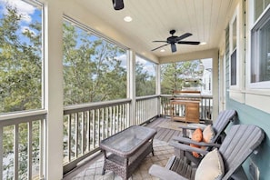 A covered porch with a ceiling fan, a table, and chairs. - Community Pool, Sleeps 10, Sunrise & Serenity, Bikes (Seagrove Beach)
