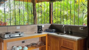 A kitchen with wooden cabinets, a gas stove, a coffee maker, and a sink. - Ceiba EcoContainer / La Fortuna / Jacuzzi - AC - WIFI. (Agua Azul)