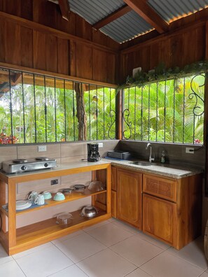 A kitchen with wooden cabinets, a gas stove, a coffee maker, and a sink. - Ceiba EcoContainer / La Fortuna / Jacuzzi - AC - WIFI. (Agua Azul)