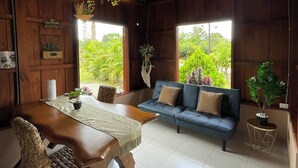 A wooden interior with a dining table, chairs, a sofa, and hanging plants. - Ceiba EcoContainer / La Fortuna / Jacuzzi - AC - WIFI. (Agua Azul)