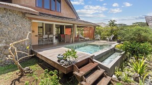 Ein Haus mit Steinaußenfassade, einer Holzdachterrasse, einem Swimmingpool und einer überdachten Terrasse.