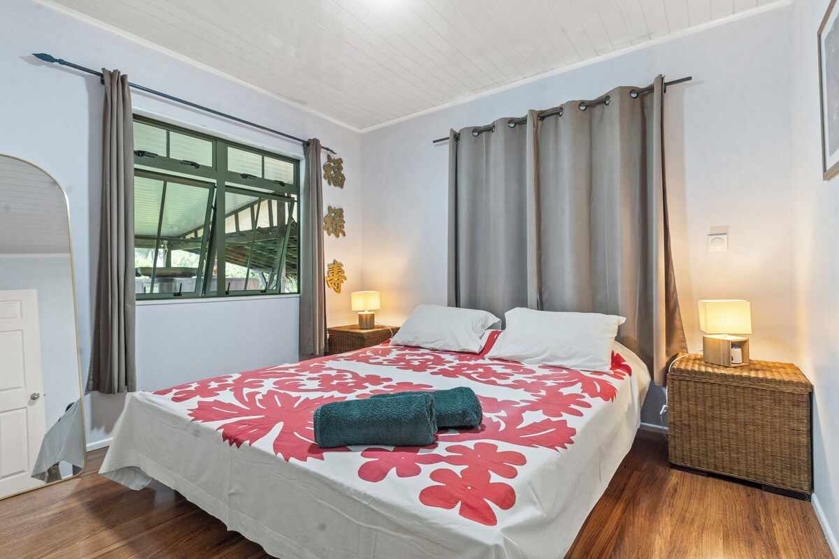 A bedroom with a bed, two bedside tables, a window, and a door.