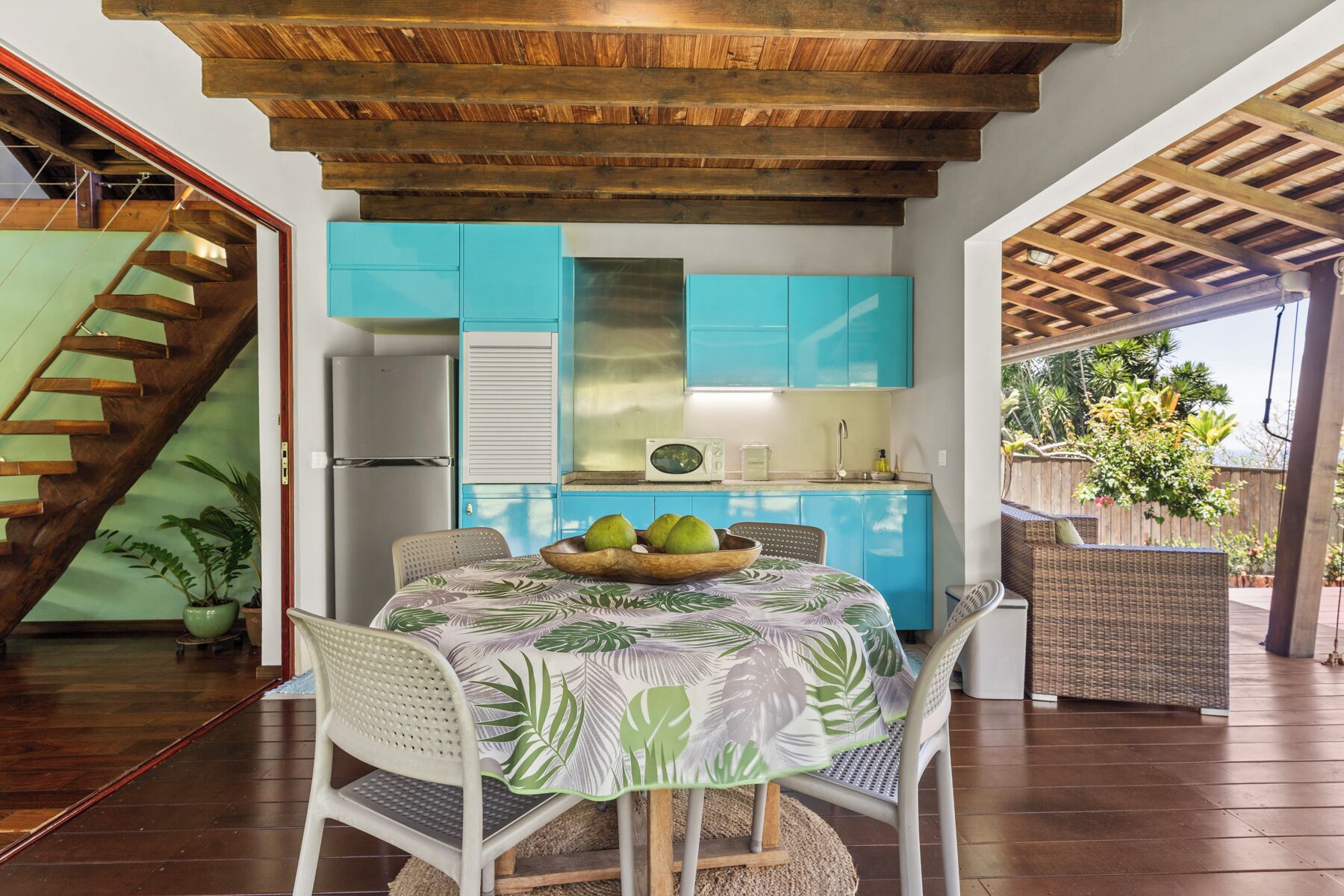 A kitchen with blue cabinets, a wooden ceiling, and a dining area with a table set for two.
