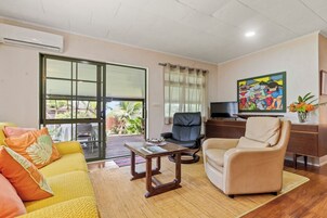 Una sala de estar con un sofá, una mesa de centro, una silla, un escritorio y una televisión.