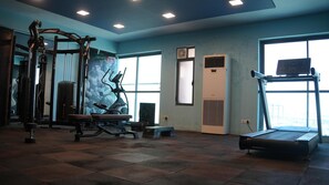 A gym with exercise equipment, large windows, and a treadmill. - The grand morning sweetes (Jaipur)