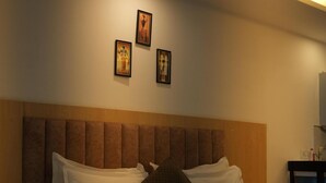 Un dormitorio con cabecera de madera, cama con ropa de cama blanca y tres cuadros en la pared.