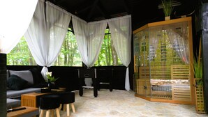 A cozy room with a stone floor, a sofa, a coffee table, and a wooden cabinet. - Forest home with pool, jacuzzi and sauna for relaxing and fun (Ivanec)