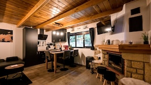 A cozy kitchen with wooden beams, a dining area, and a fireplace. - Forest home with pool, jacuzzi and sauna for relaxing and fun (Ivanec)
